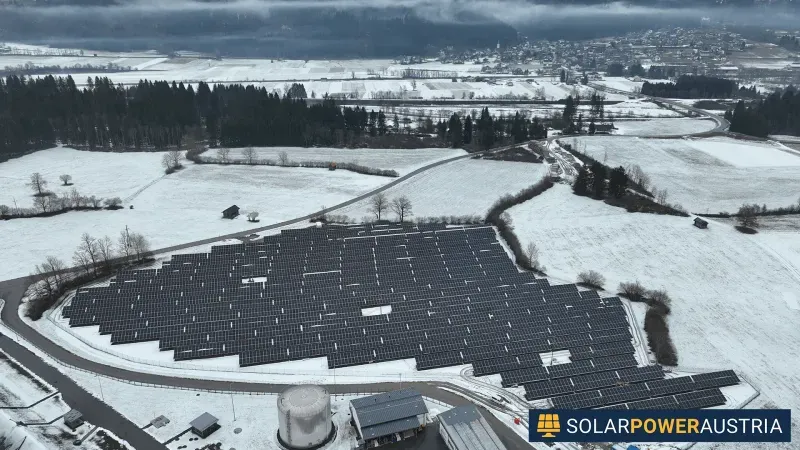 Luftaufnahme einer weitläufigen Photovoltaik-Freiflächenanlage in verschneiter Landschaft
