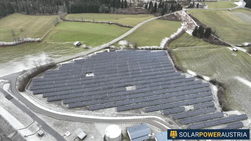 Luftaufnahme einer Photovoltaik-Freiflächenanlage auf einer Wiese am Ortsrand