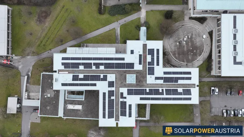 Luftaufnahme eines weitläufigen Gebäudekomplexes mit mehreren Photovoltaik-Feldern