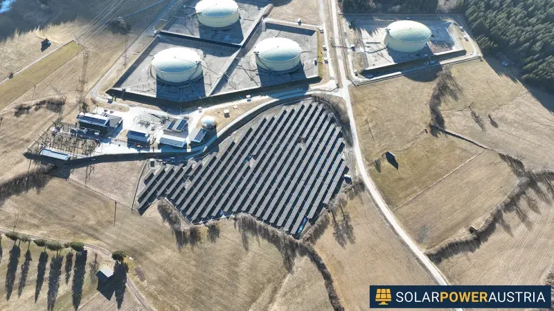 Luftaufnahme einer Photovoltaik-Freiflächenanlage neben einem Industriebetrieb