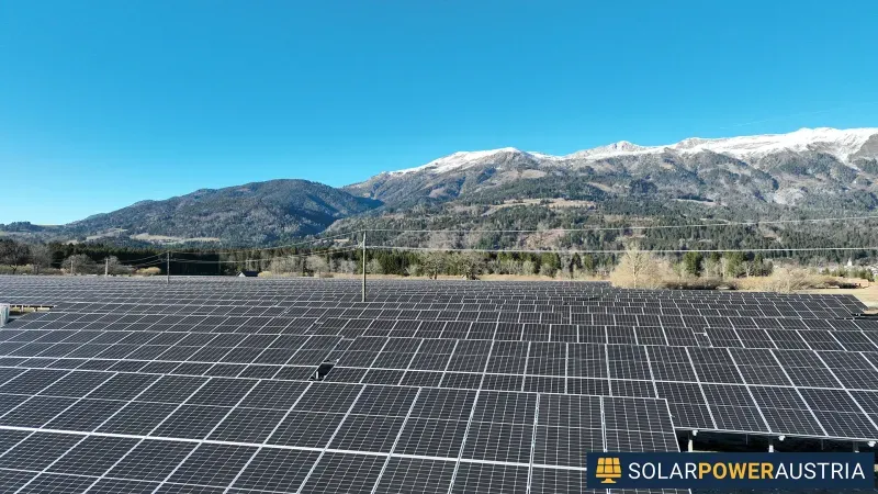 Luftaufnahme einer großflächigen Photovoltaik-Anlage vor Bergkulisse