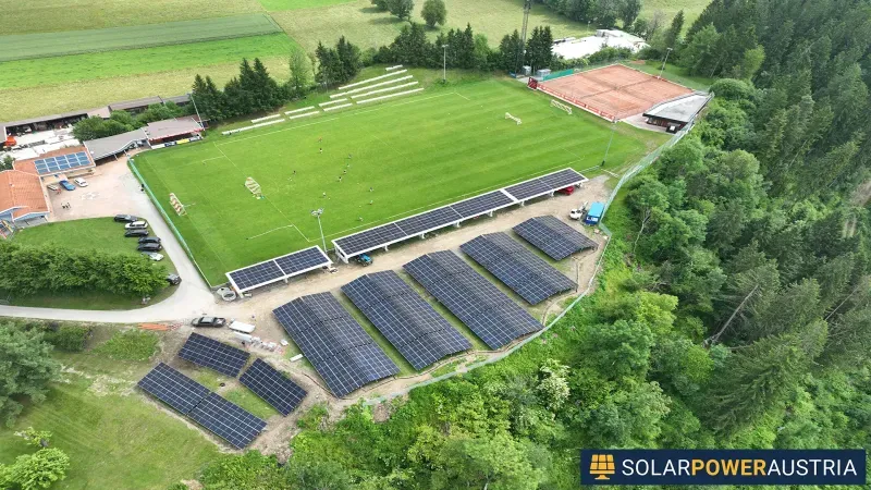 Luftaufnahme einer Photovoltaik-Freiflächenanlage neben einem Sportplatz