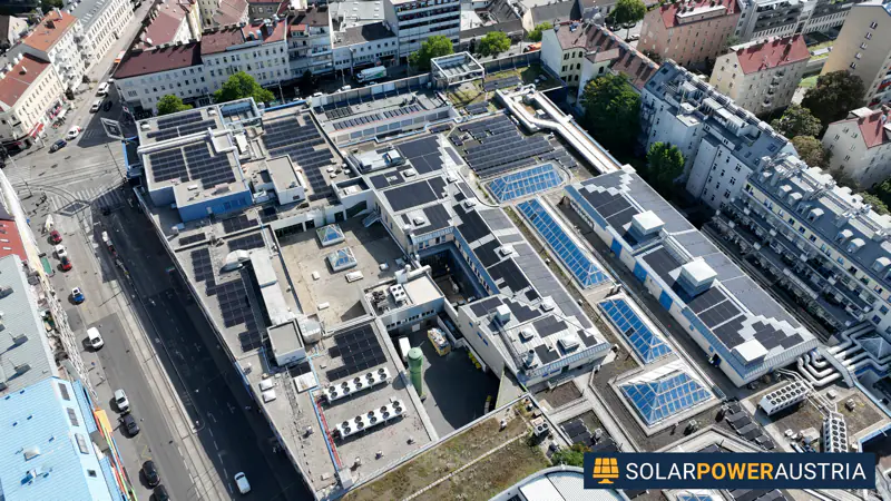 Luftaufnahme mehrerer Photovoltaik-Dachanlagen auf einem Gebäudekomplex in dichter Stadtbebauung