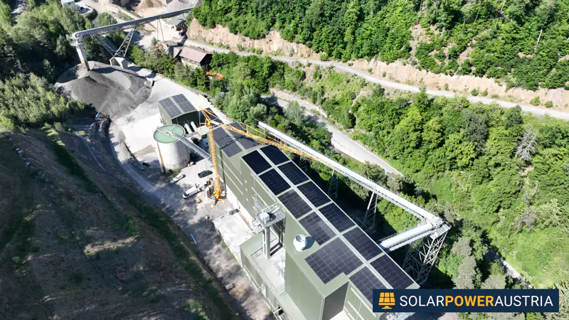 Luftaufnahme einer Photovoltaik-Anlage auf dem Dach eines Betriebsgebäudes am Hang
